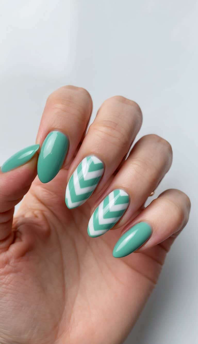 A close-up of green almond-shaped nails with seafoam chevron designs