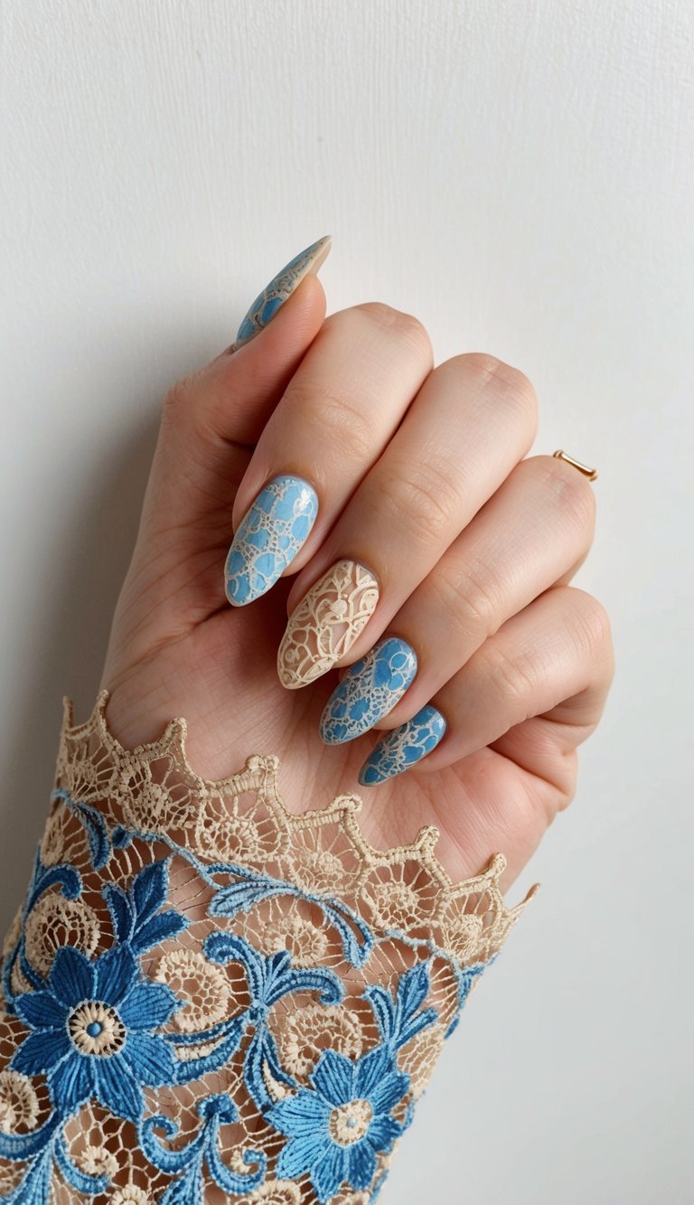 A close-up of a hand wearing an embroidered sleeve highlights blue almond nails detailed with white lace designs and a single cream-toned accent nail.