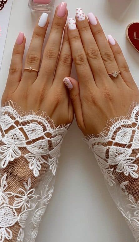 A table with various nail polish bottles, heart-shaped stickers, and delicate lace patterns laid out for Valentine's Day nail art inspiration