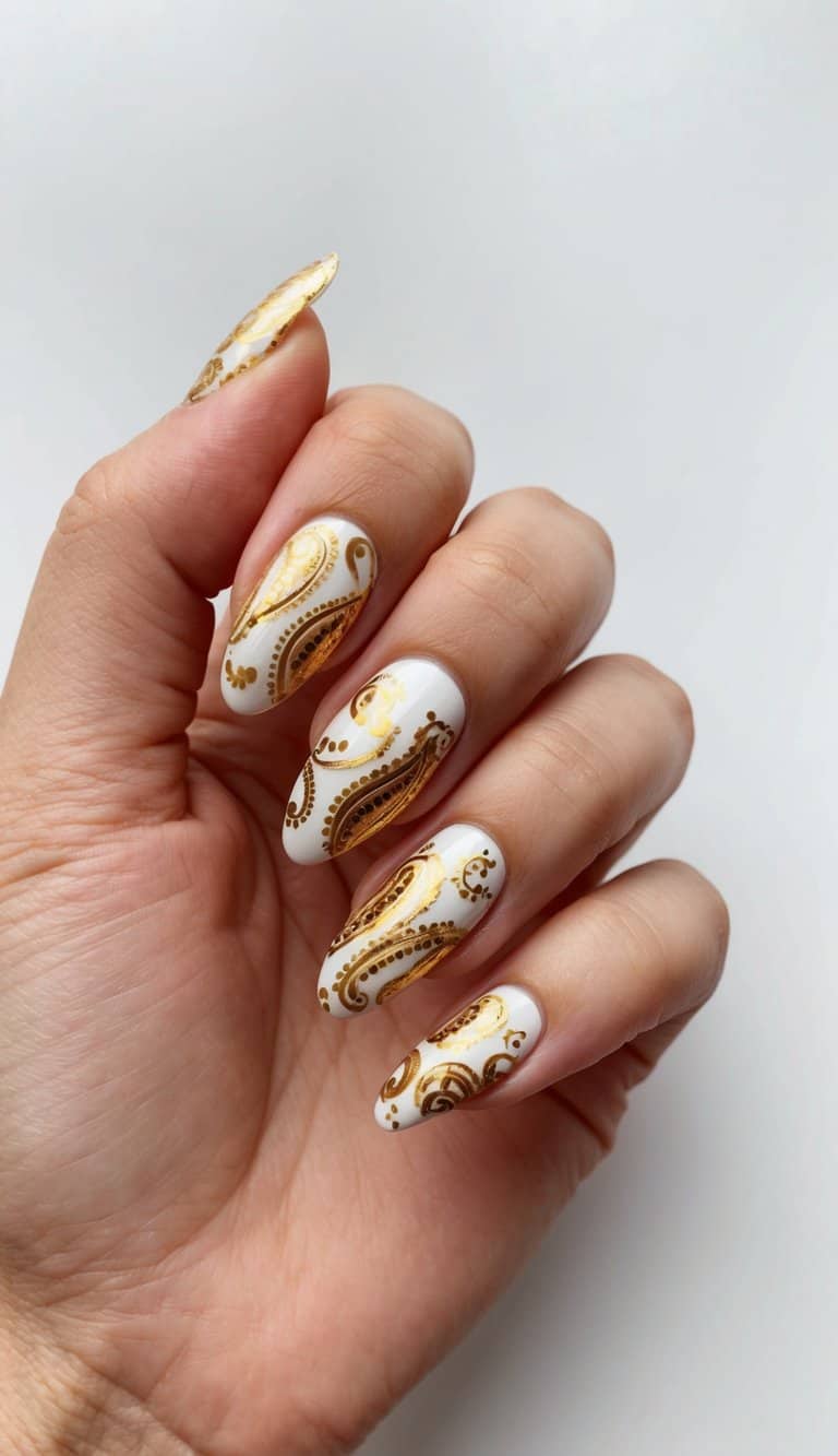 A close-up of golden paisley patterns on acrylic nails