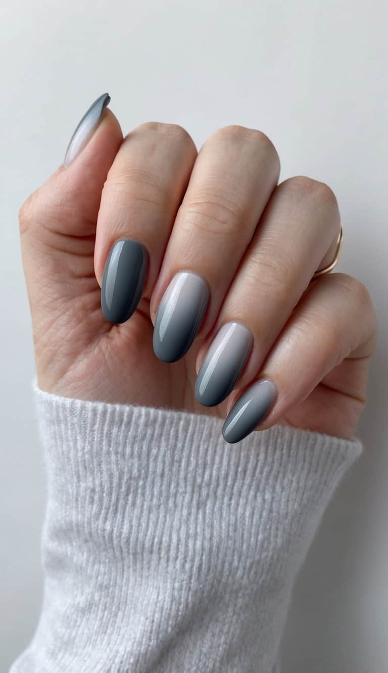 A close-up of charcoal gray ombre nail art on a clean, neutral background