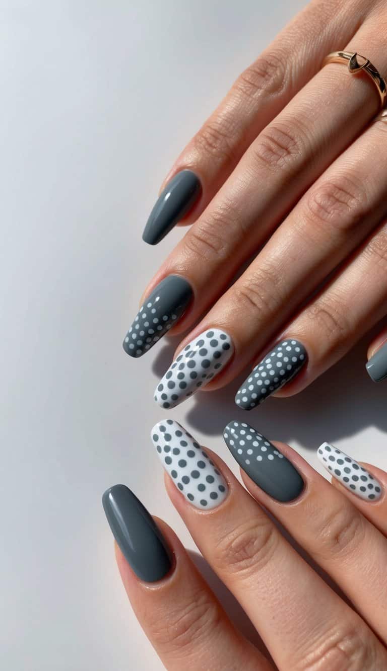 A close-up of charcoal gray and white dotted nail art on a sleek, manicured surface