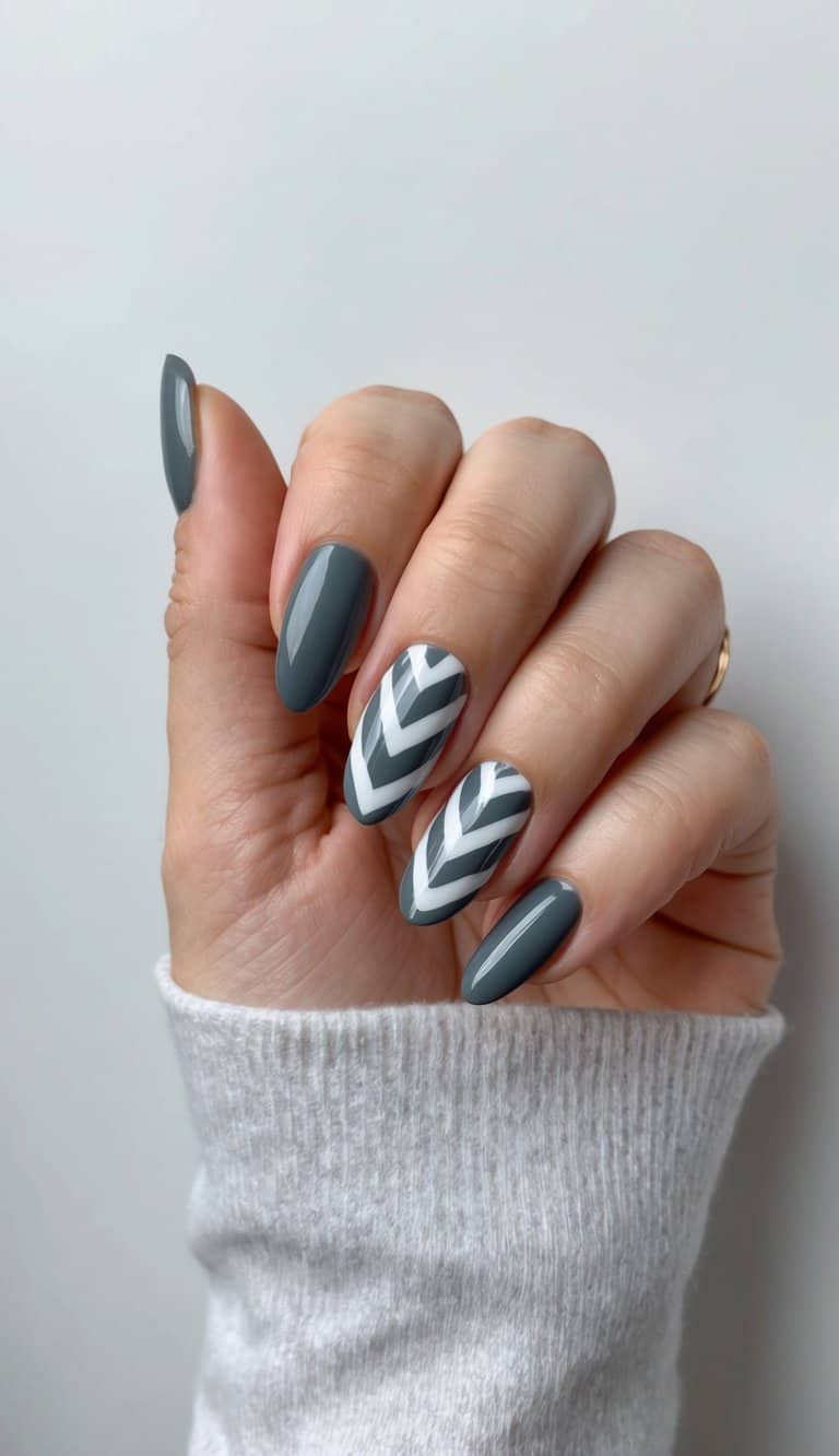 A close-up of charcoal gray chevron pattern nail art on a clean, neutral background