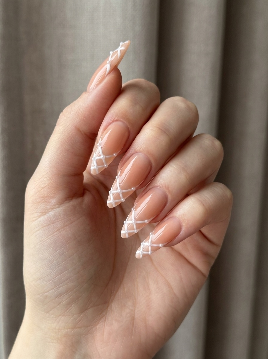 Artfully posed hand featuring translucent peach nails with fine white lines in a net-like pattern and small pearl drops at each intersection—a delicate, stitched-style peach nail art idea.