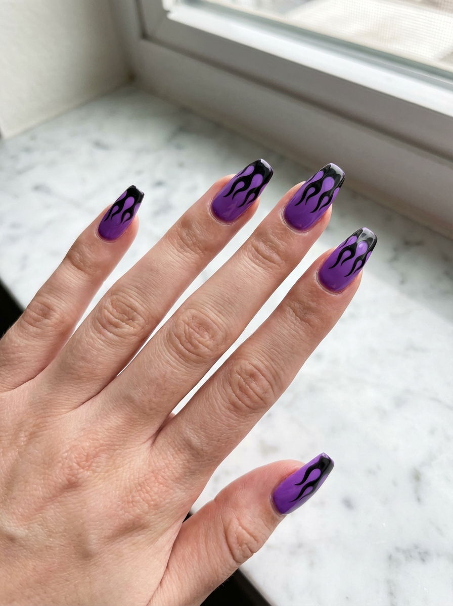 Resting beside a window on a marble countertop, fingers show purple nails topped with black flame artwork across the tips, highlighting a purple and black nail art idea.