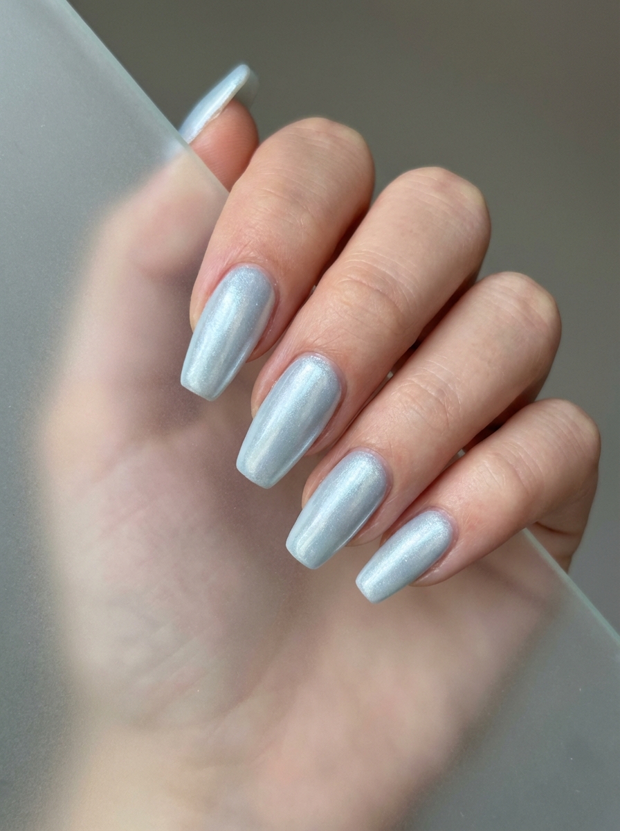 Hand with long tapered nails painted in a futuristic silver chrome finish—perfect for a standout prom nail art idea with metallic shine.