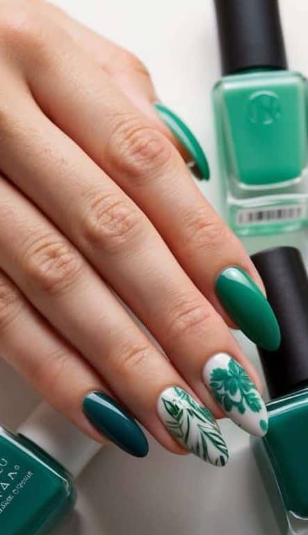 A table with various shades of green nail polish bottles and almond-shaped nails with different intricate designs
