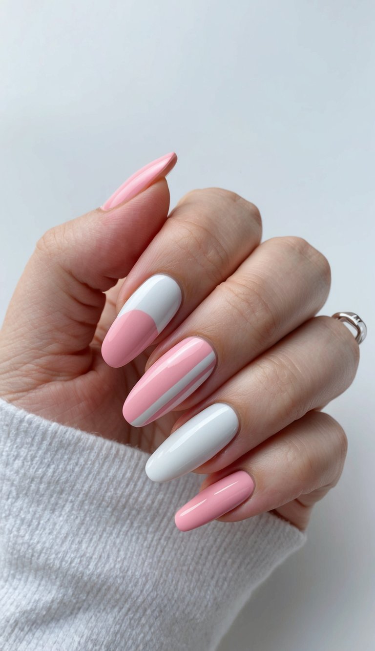 Hand with almond-shaped nails showing a pink and white nail art idea featuring vertical stripes, soft half-moons, and a glossy pastel finish.