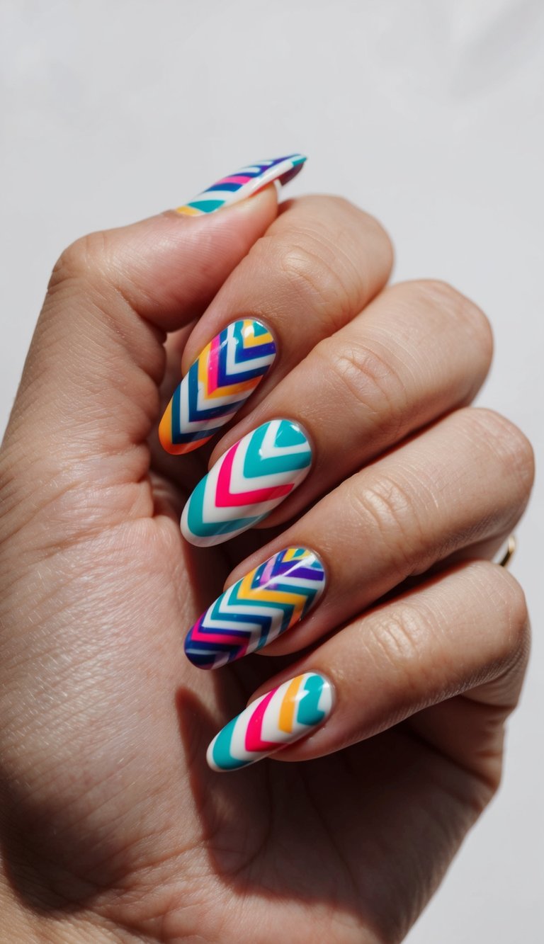 Close-up of a hand showing pretty nail art ideas with almond-shaped nails painted in bold multicolor chevron zigzag patterns featuring teal, pink, orange, purple, and blue stripes.