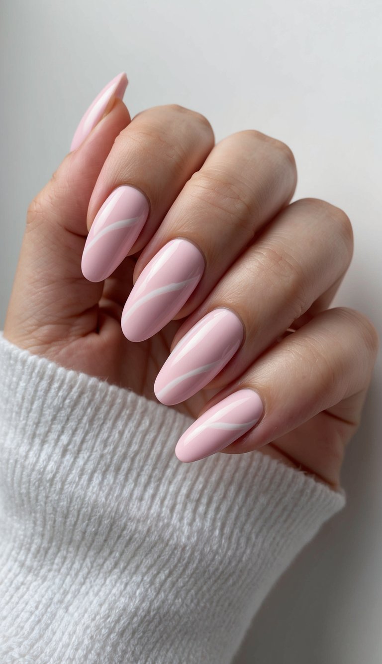 Hand partially tucked in a white sweater featuring a bridesmaid nail art idea with pastel blush manicure and thin white swirl accents on almond-shaped nails