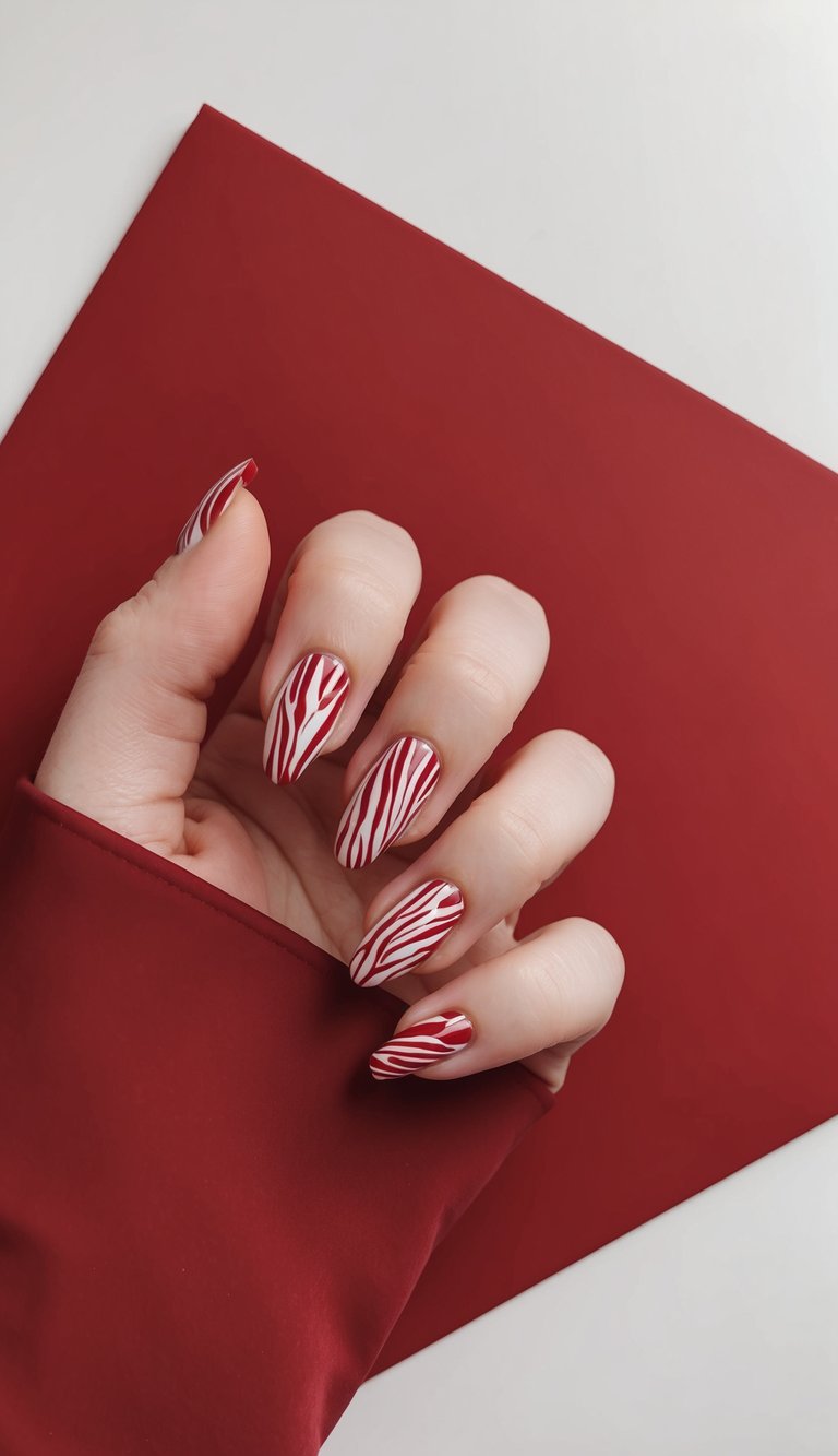 Soft hand wrapped in red fabric reveals a cute red nail art idea, with high-gloss red polish accented by playful, narrow white striping across each nail.