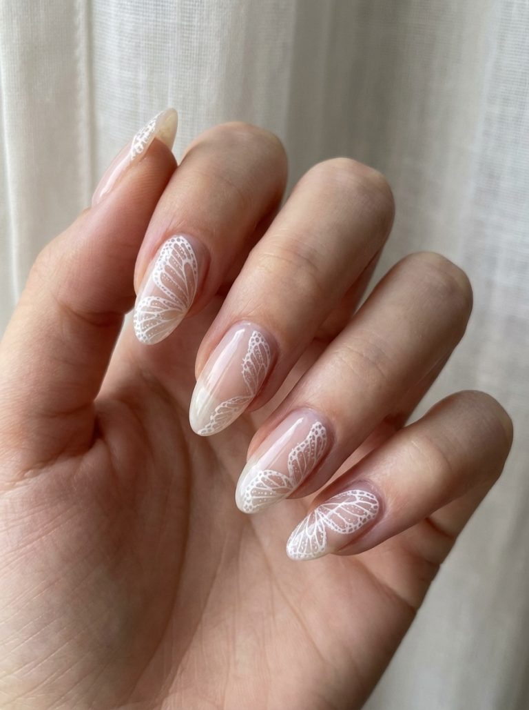 A hand displaying long, almond-shaped nails with a light, translucent base and intricate white butterfly wing designs on each nail.