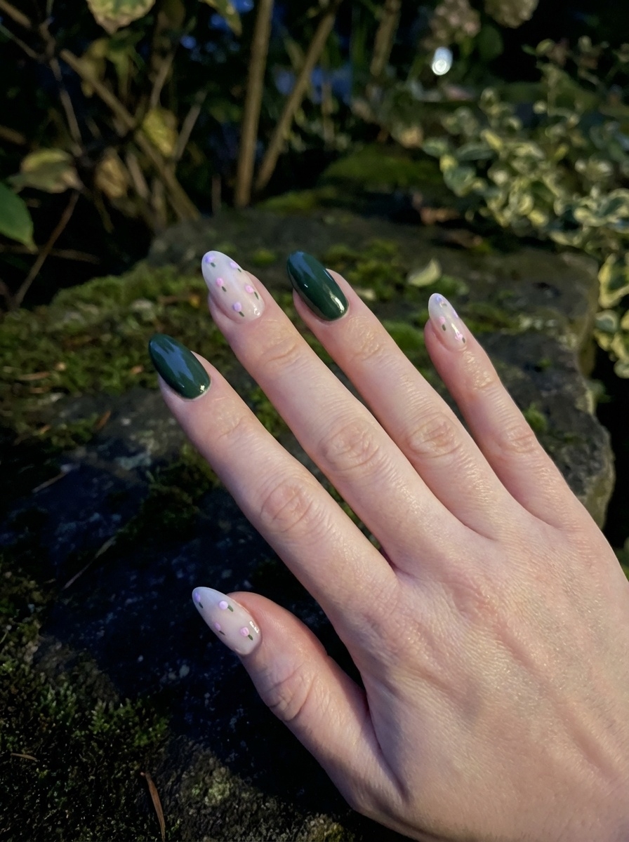 Angled outdoor beauty shot highlighting an aesthetic nail art idea with alternating forest-green nails and nude transparent nails decorated with tiny colorful dots.