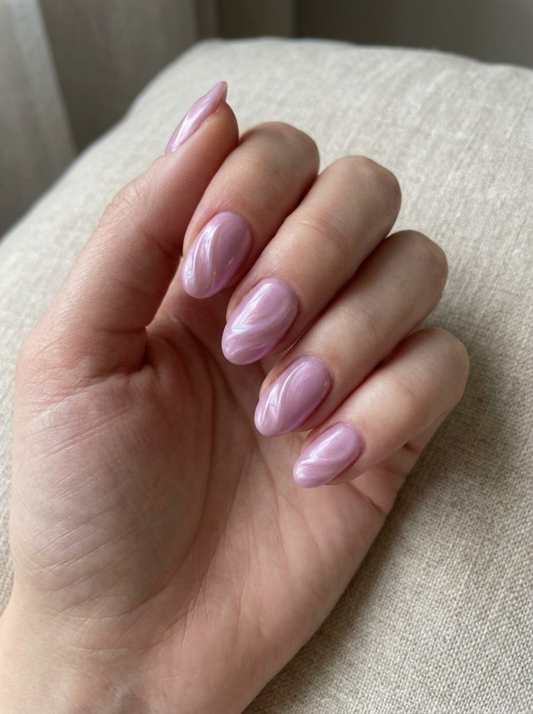 A hand with long, almond-shaped nails painted in a glossy, marbled lilac design.