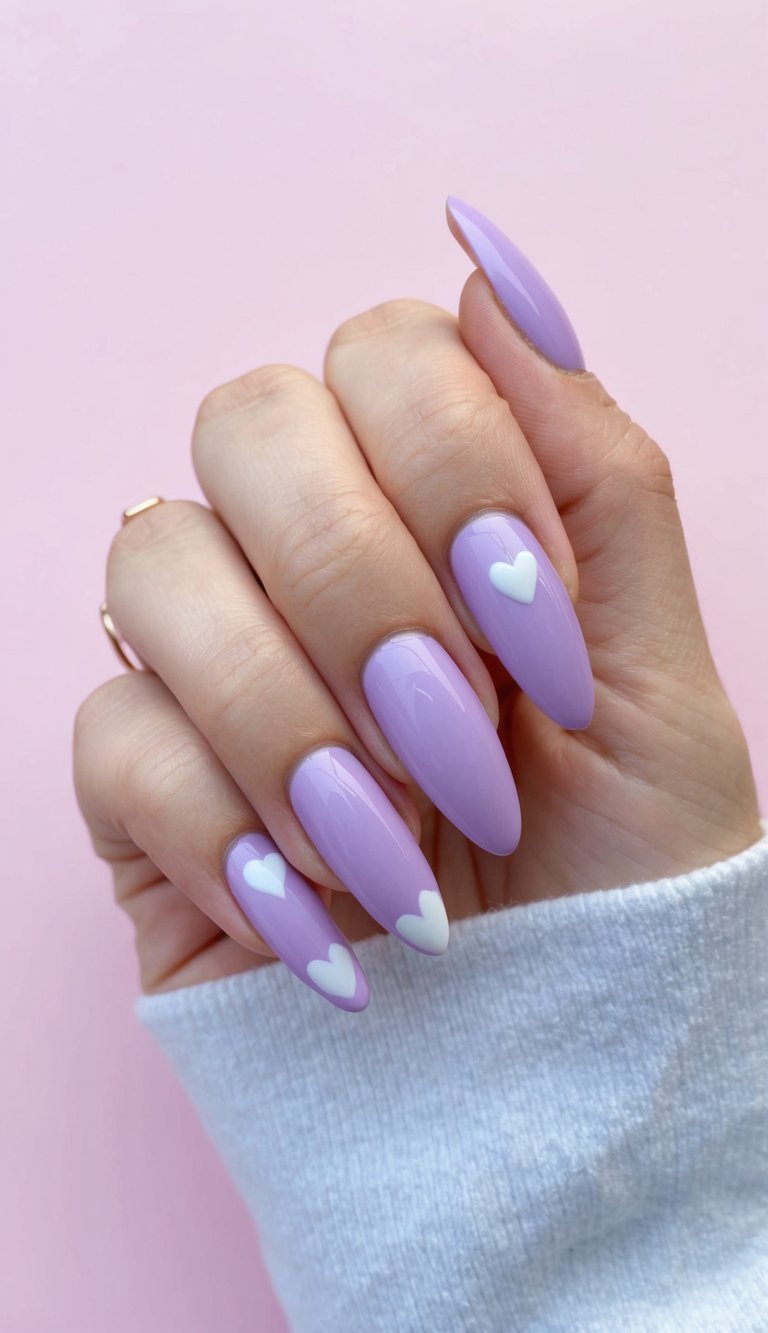 A manicured hand posed against a soft pink background, highlighting a lilac nail art idea with shiny purple nails and subtle white heart accents on select fingers.