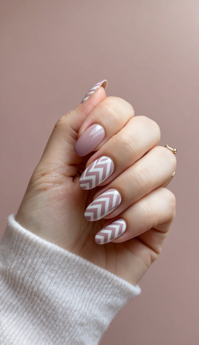 Hand partially wrapped in a soft sweater showcasing a mauve nail art idea with almond-shaped nails, glossy mauve polish, and white chevron patterns on accent nails.