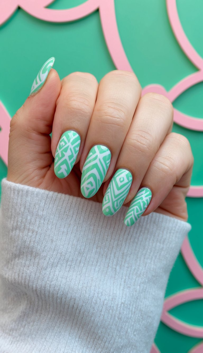 A hand shows a mint green nail art idea featuring almond-shaped nails with white geometric line designs against a green and pink patterned background.