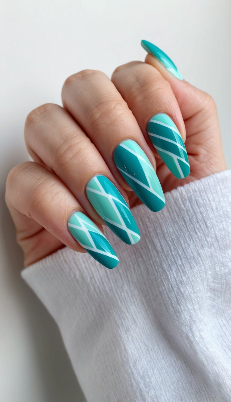 Natural-light image of a hand featuring a teal nail art idea with long coffin-shaped teal nails decorated with fluid white diagonal line designs.