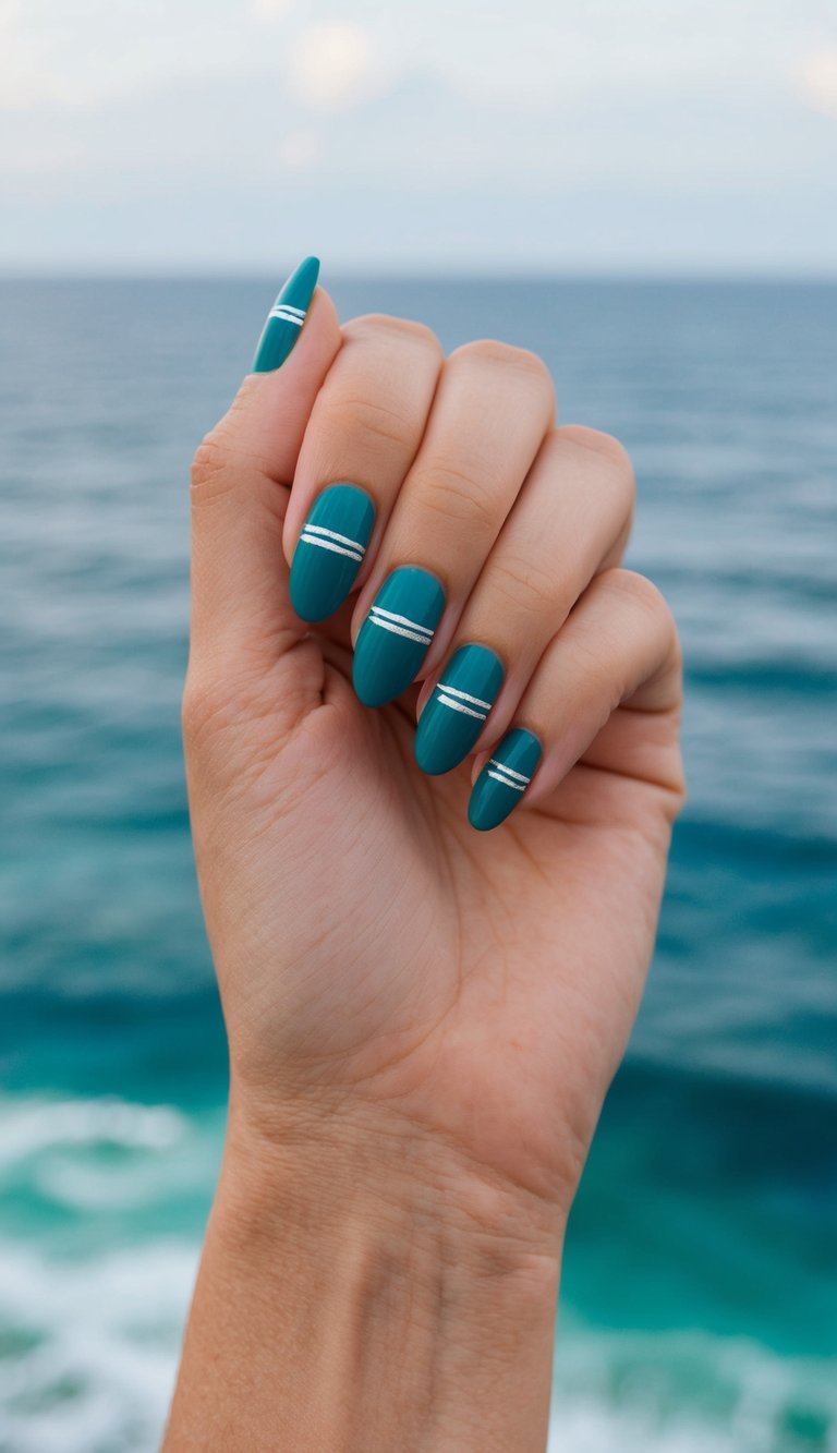Teal-painted nails with minimal white horizontal lines are displayed on a hand held up near the sea, with waves softly blurred in the background.