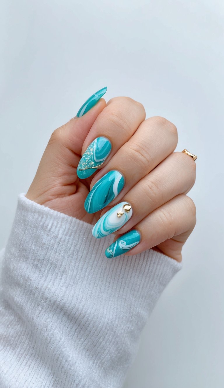 A close-up of a hand reveals glossy teal nails with white marble patterns and gold detailing, styled with a cozy sweater sleeve in soft daylight.
