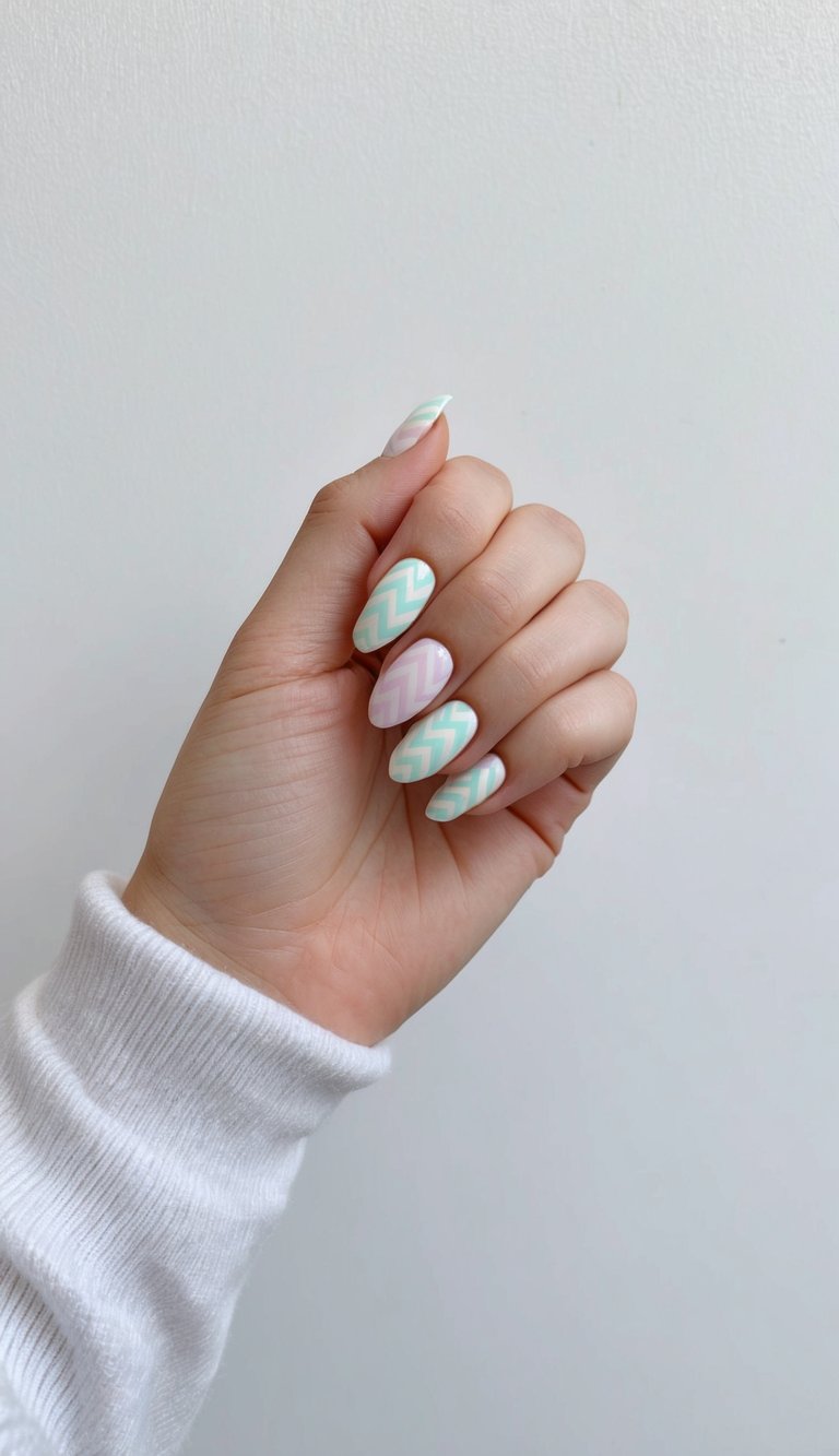 Minimal studio image of fingers displaying an aesthetic nail art idea with pastel zigzag nail designs in mint green and soft purple tones.