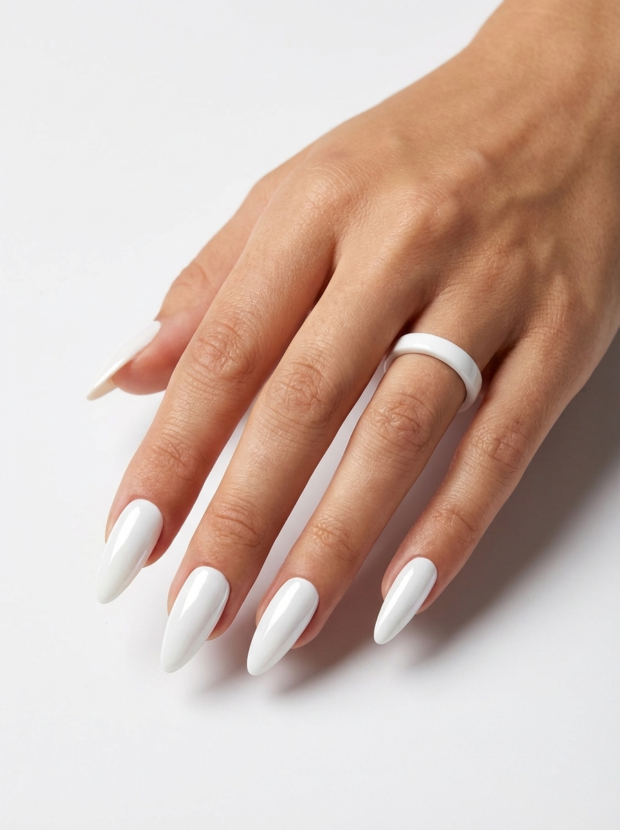 Manicured hand with glossy white almond nails and a simple white band ring positioned against a pale background, capturing a chic minimalist bridal nail art idea.