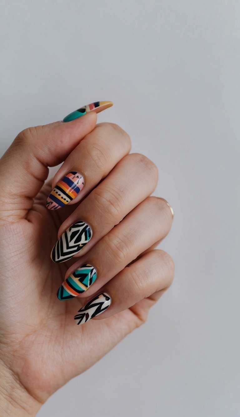 Fingers curled slightly showing a short nail art idea with colorful geometric nail art including zigzags, stripes, and tribal shapes in teal, coral, mustard, and black polish.