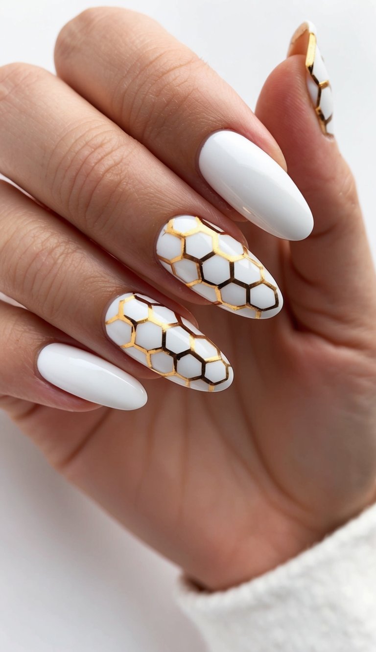 Fingers gently curved inward featuring a white and gold nail art idea with glossy white almond nails and two accent nails designed with metallic gold honeycomb hexagon outlines.