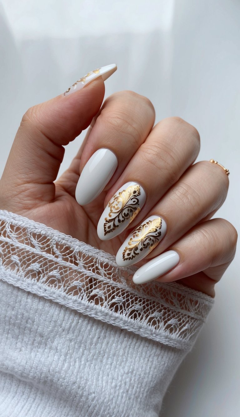 Manicured hand partly wrapped in a lace-edged sleeve showing a white and gold nail art idea with ivory almond nails and two accent nails featuring ornate metallic gold flourish designs.