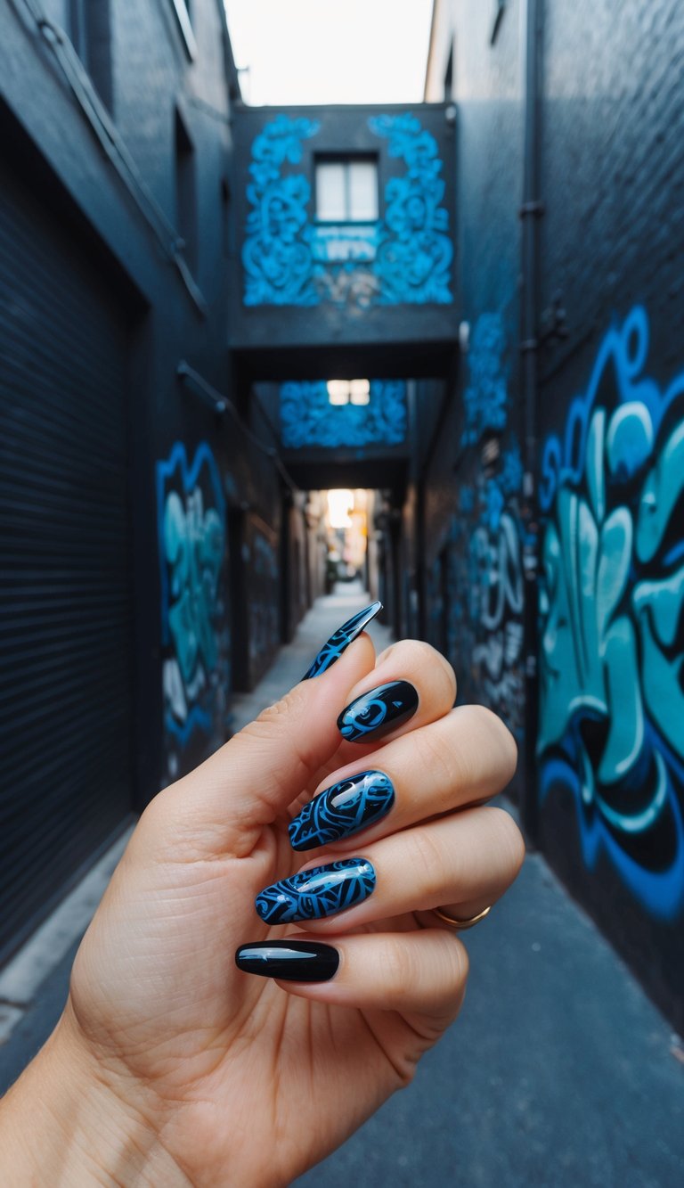 Manicured hand raised in a graffiti-covered alleyway showing a black and blue nail art idea with glossy black nails and detailed cobalt blue graffiti-inspired patterns.