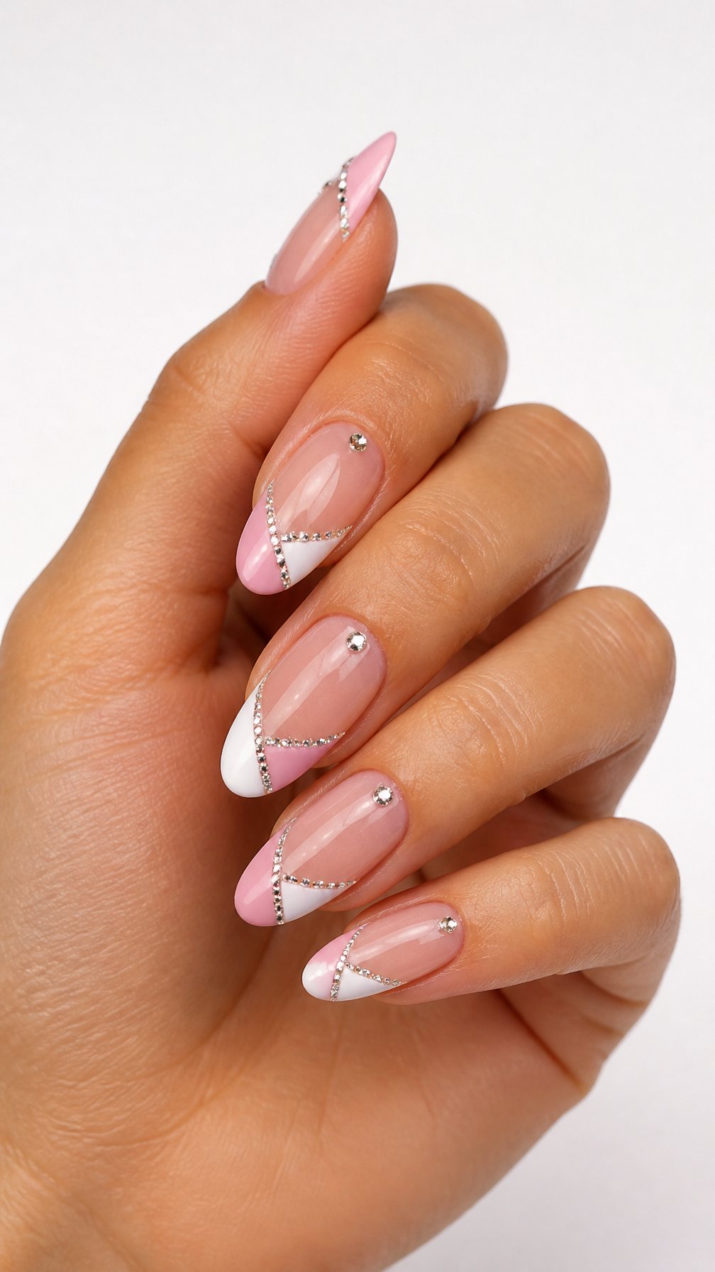 A single hand displays almond-shaped nails with two-tone French tips and sparkling rhinestone accents against a white background.
