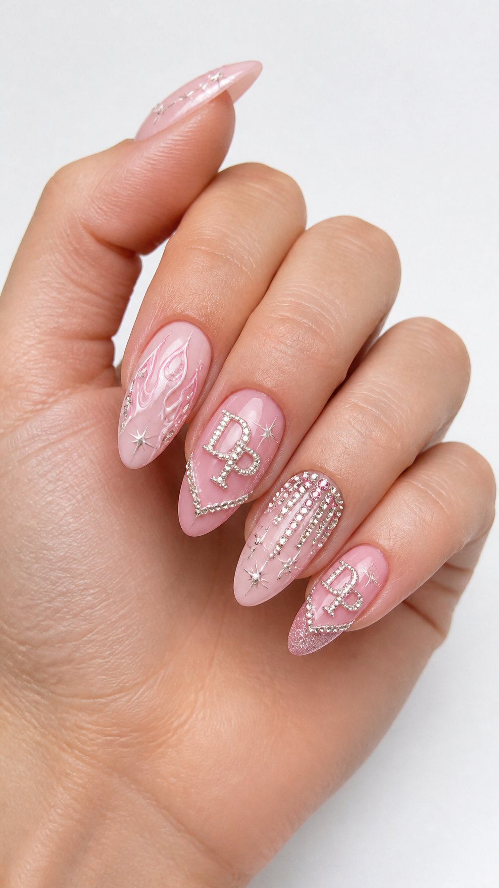 A single hand with glossy pink almond-shaped nails decorated with white and silver sparkling accents.