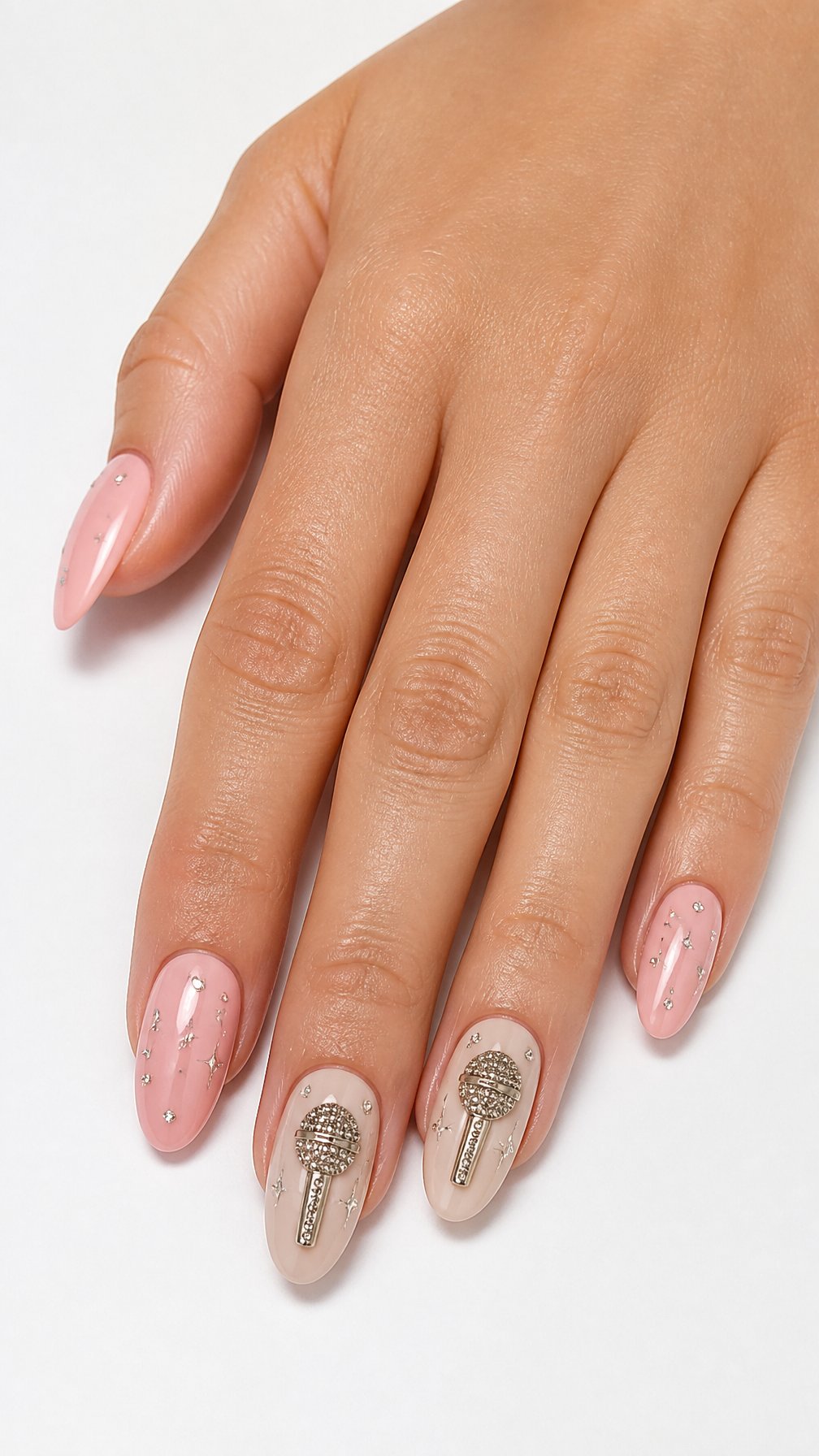 A single hand displays glossy nude nails decorated with sparkling rhinestone microphone designs against a white background.