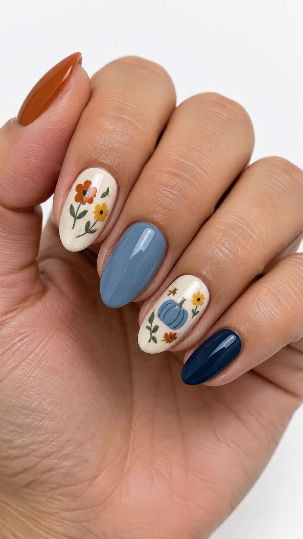 A glossy autumn manicure with small flowers and tiny blue pumpkins on several nails