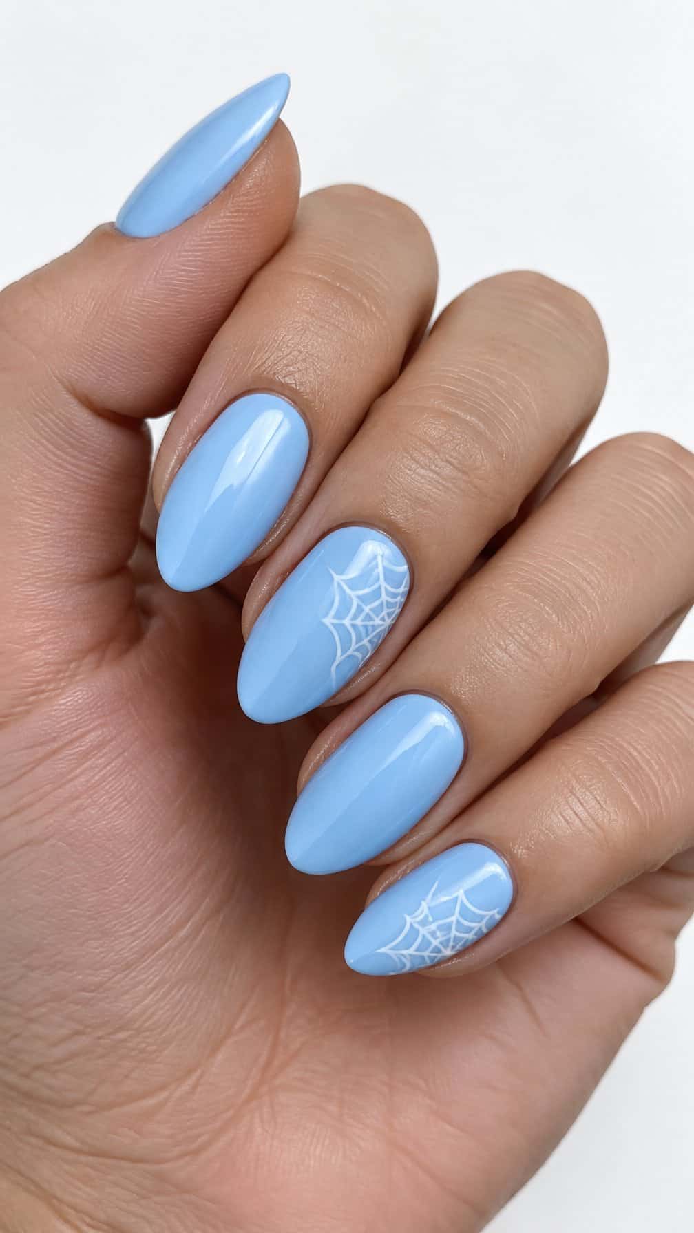 Glossy baby blue nails and white spider web designs on several accent nails