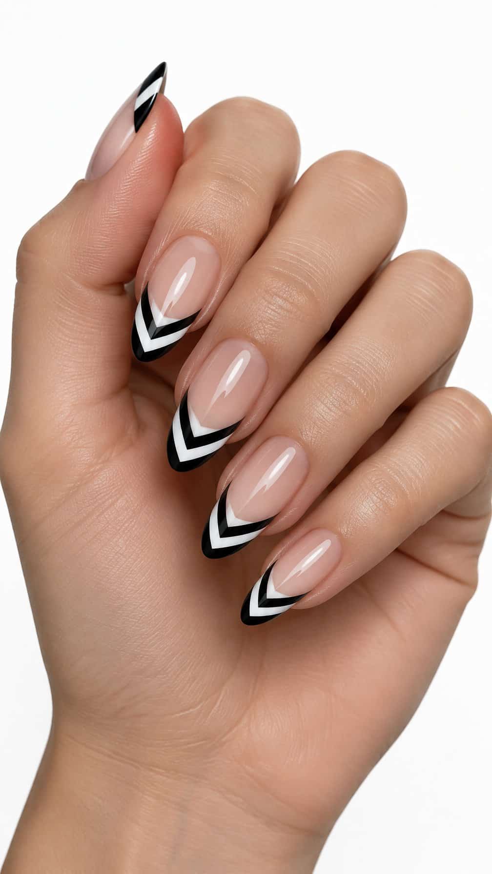 Almond-shaped nails featuring black and white chevron French tips on a nude base, photographed