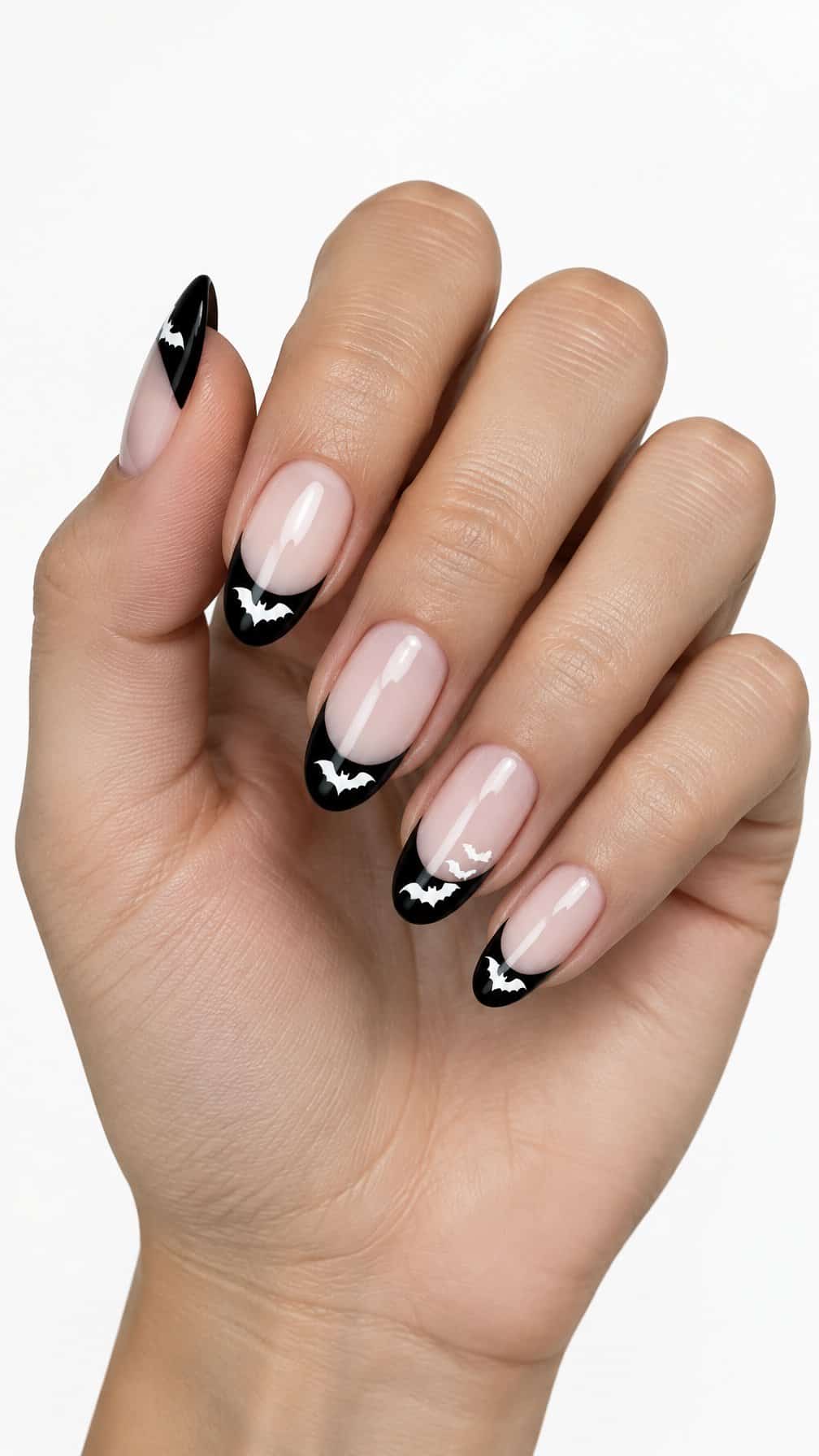 Glossy nude nails, black French tips, and small white bat designs