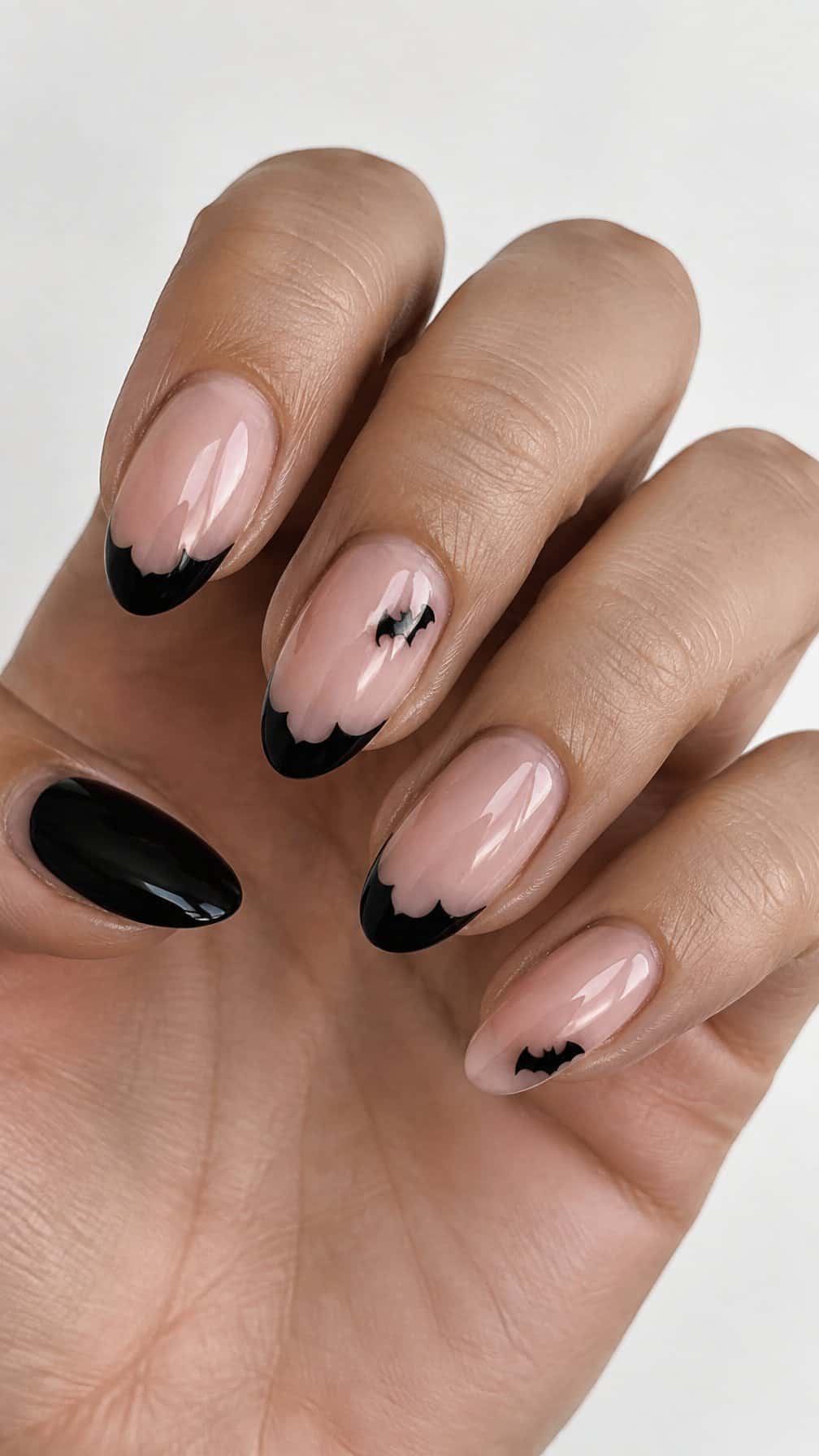 Glossy nude nails decorated with black bat-shaped French tips