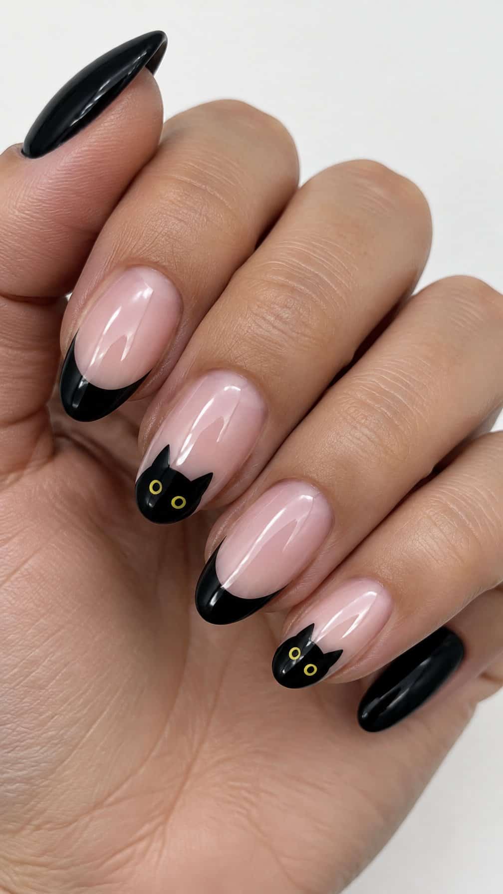 Glossy black French-tip nails and small yellow-eyed cat designs
