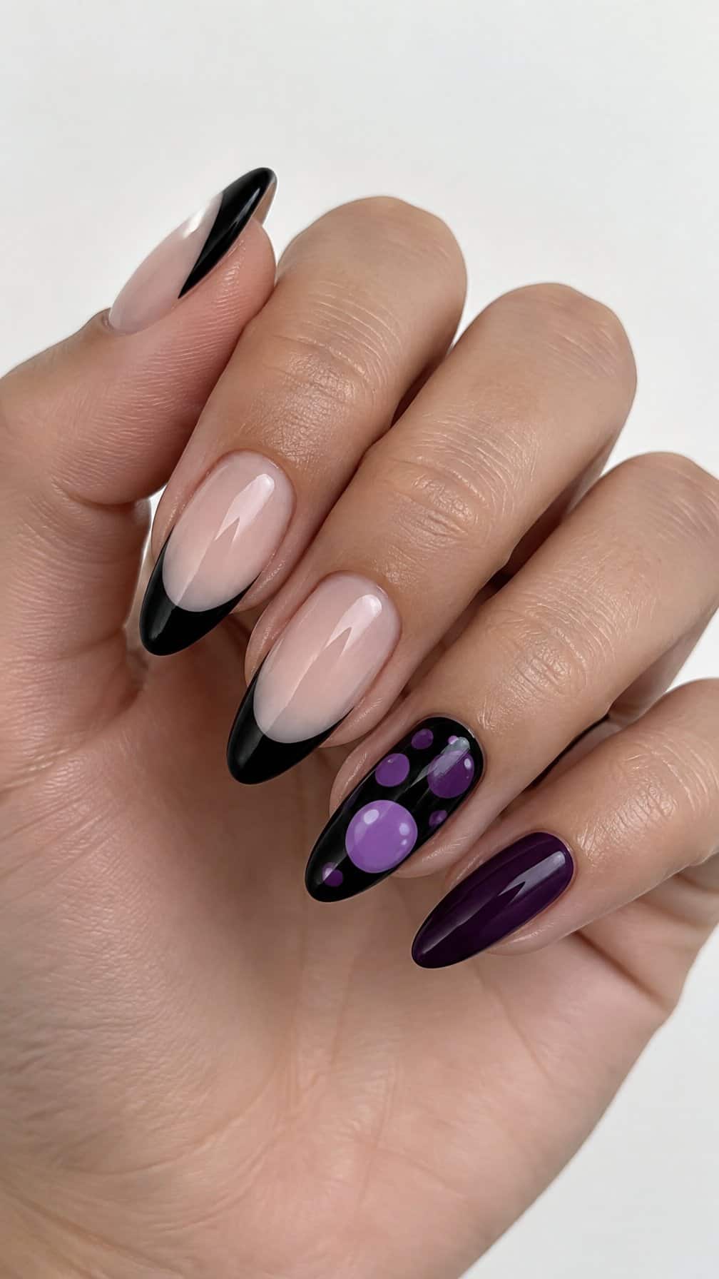 Glossy black and purple French tip nails, including purple bubble designs on one accent nail