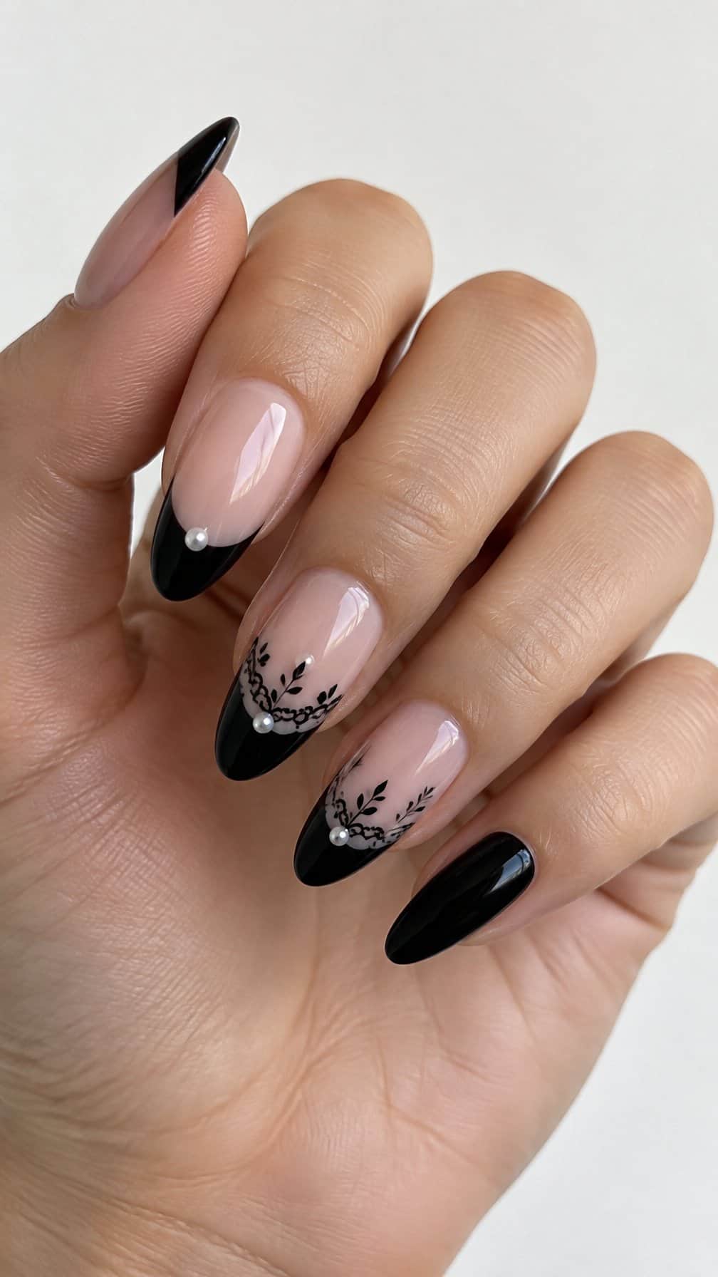 A black French tip manicure with lace details and small pearl accents