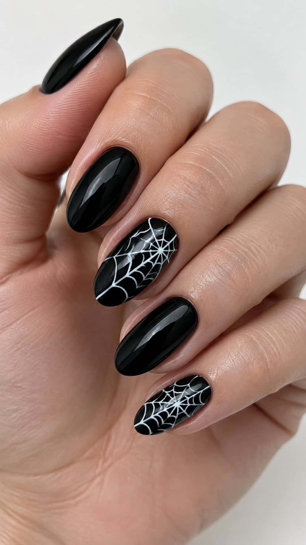 Glossy black nails, several decorated with white spider web designs