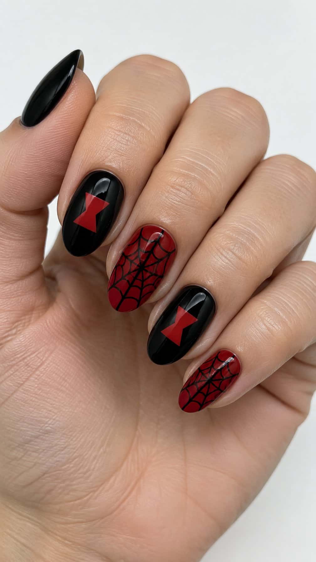 Glossy red and black nails featuring hourglass symbols and spider-web designs
