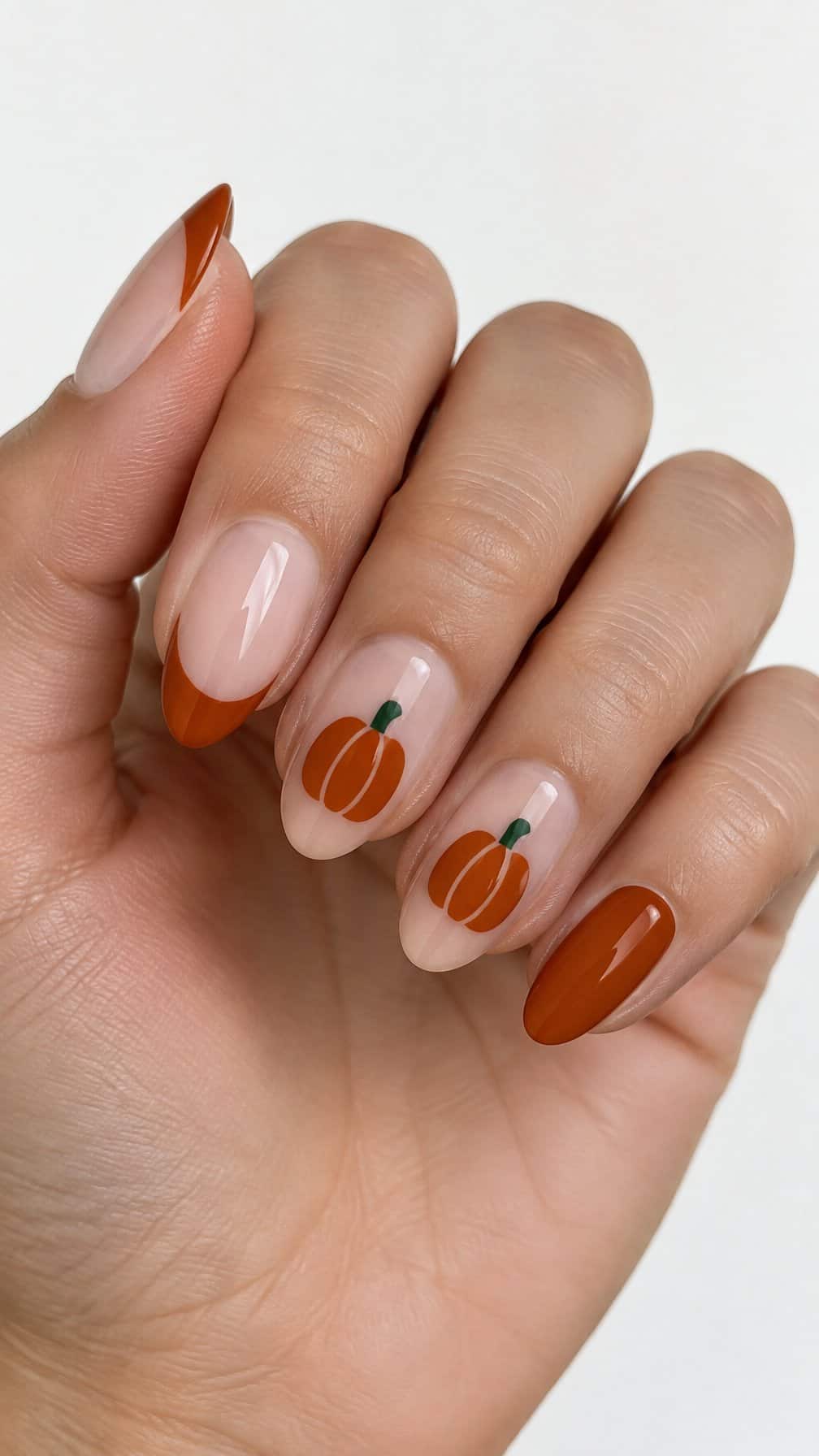Glossy burnt-orange French tip nails and pumpkin designs on two accent nails