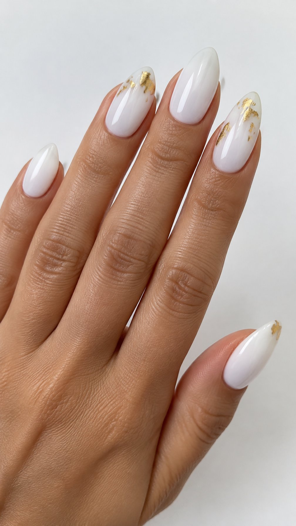 Glossy milky white nails decorated with small gold accents