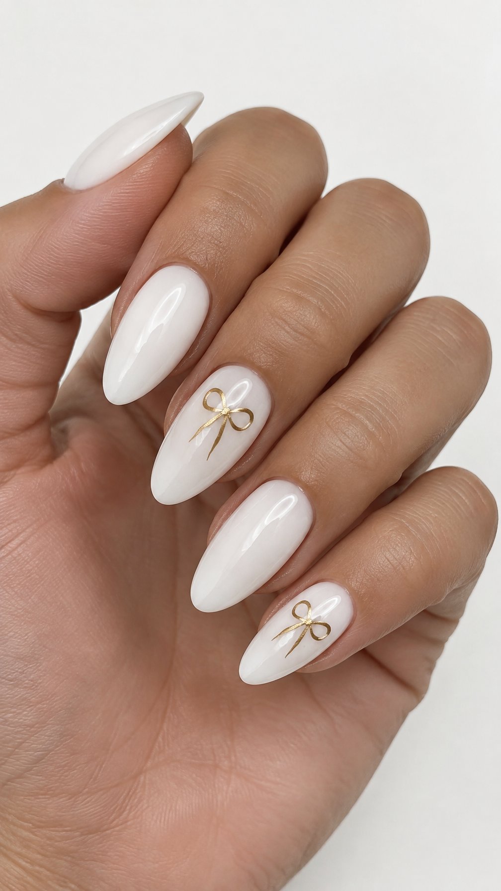 Glossy white nails decorated with small gold bows