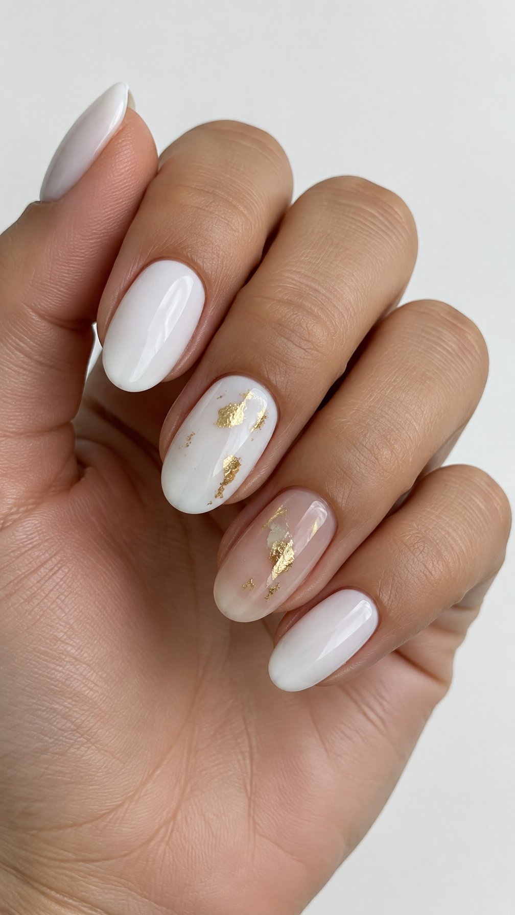 Glossy white nails decorated with scattered gold flakes
