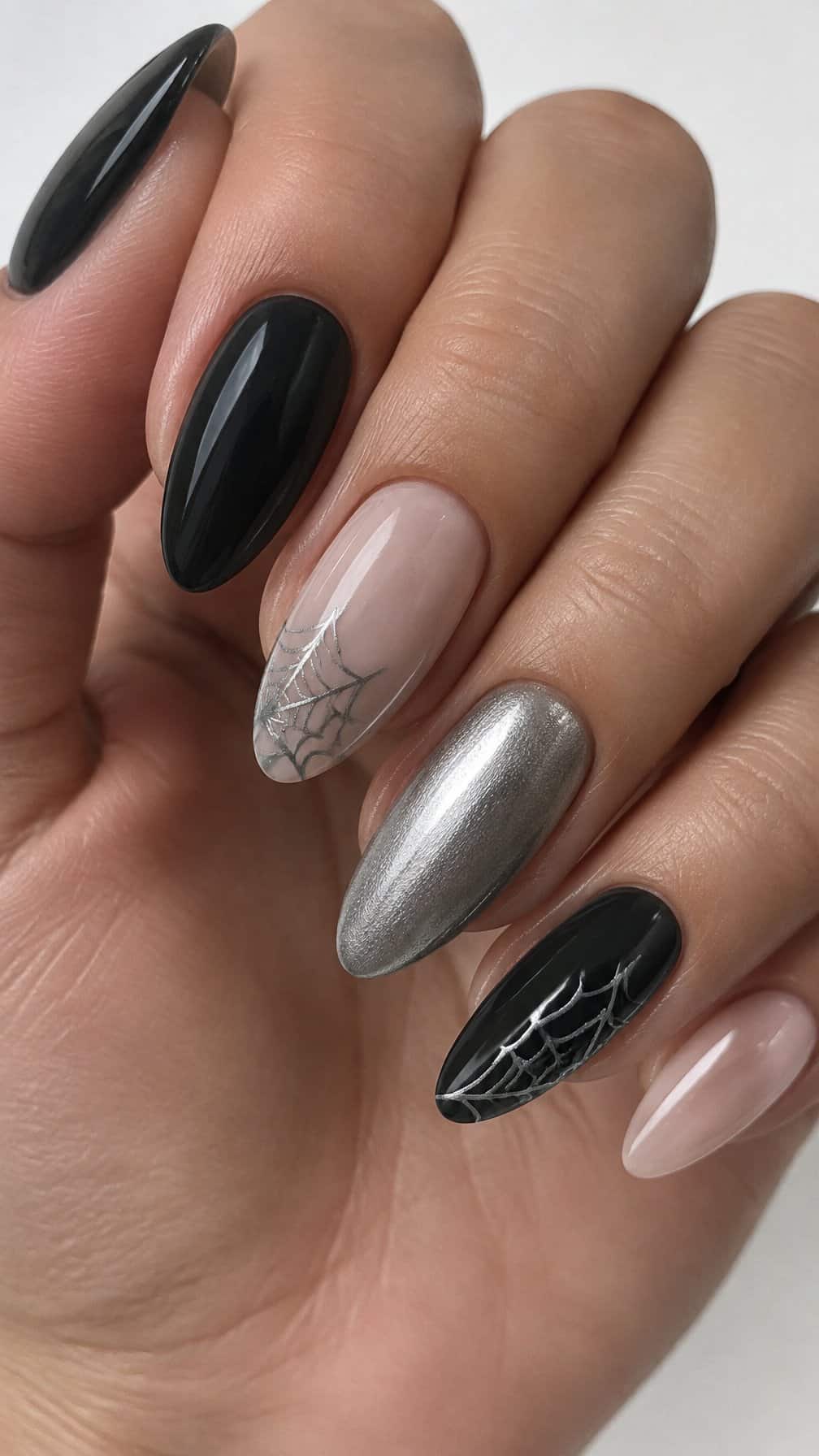 Glossy black, silver, and nude nails featuring delicate silver spider web designs