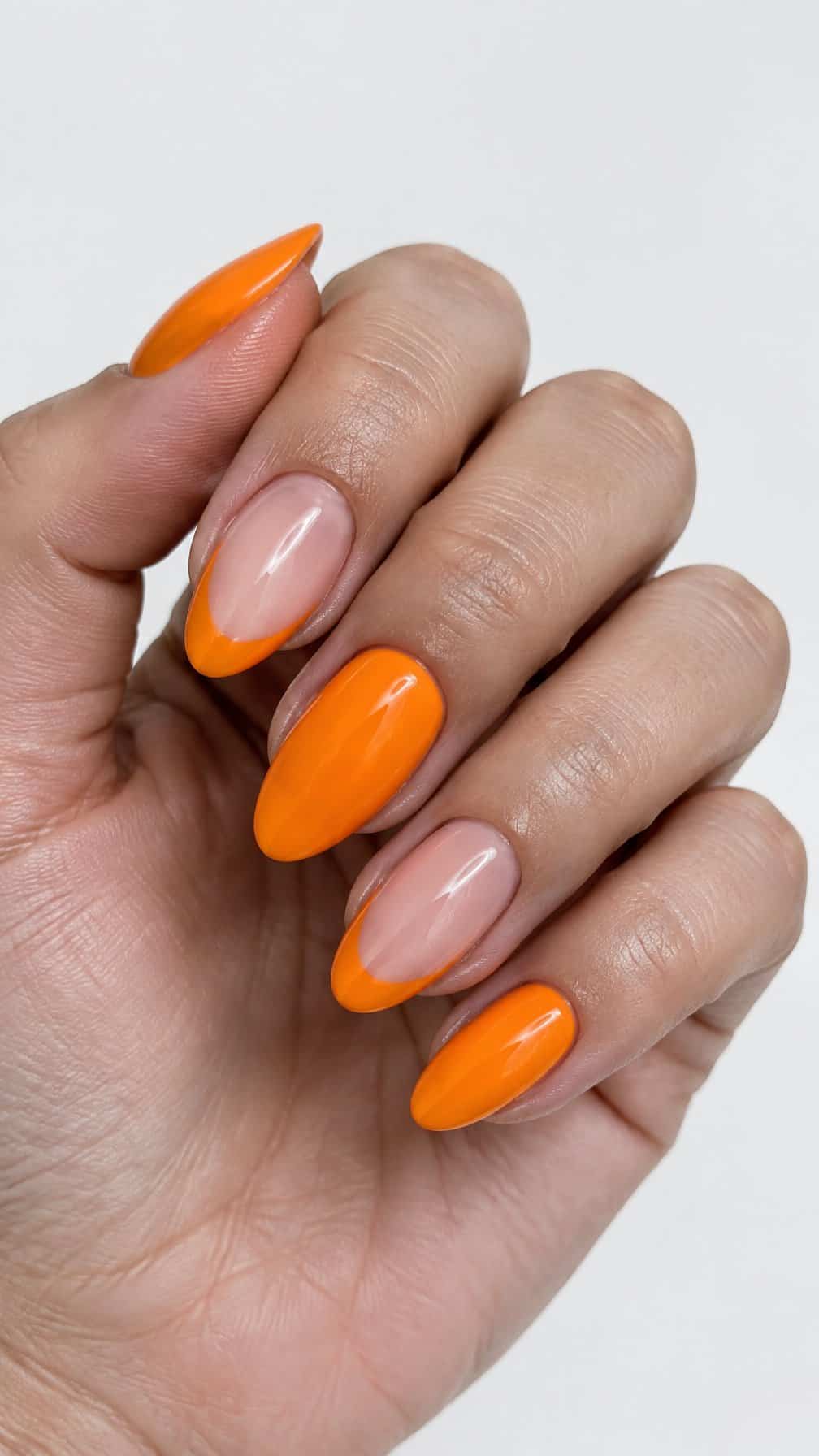 A close-up photograph of one hand with glossy orange French tip nails
