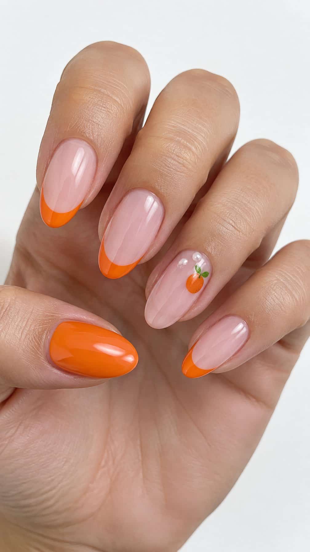 Glossy orange French tip nails and small pearl accents